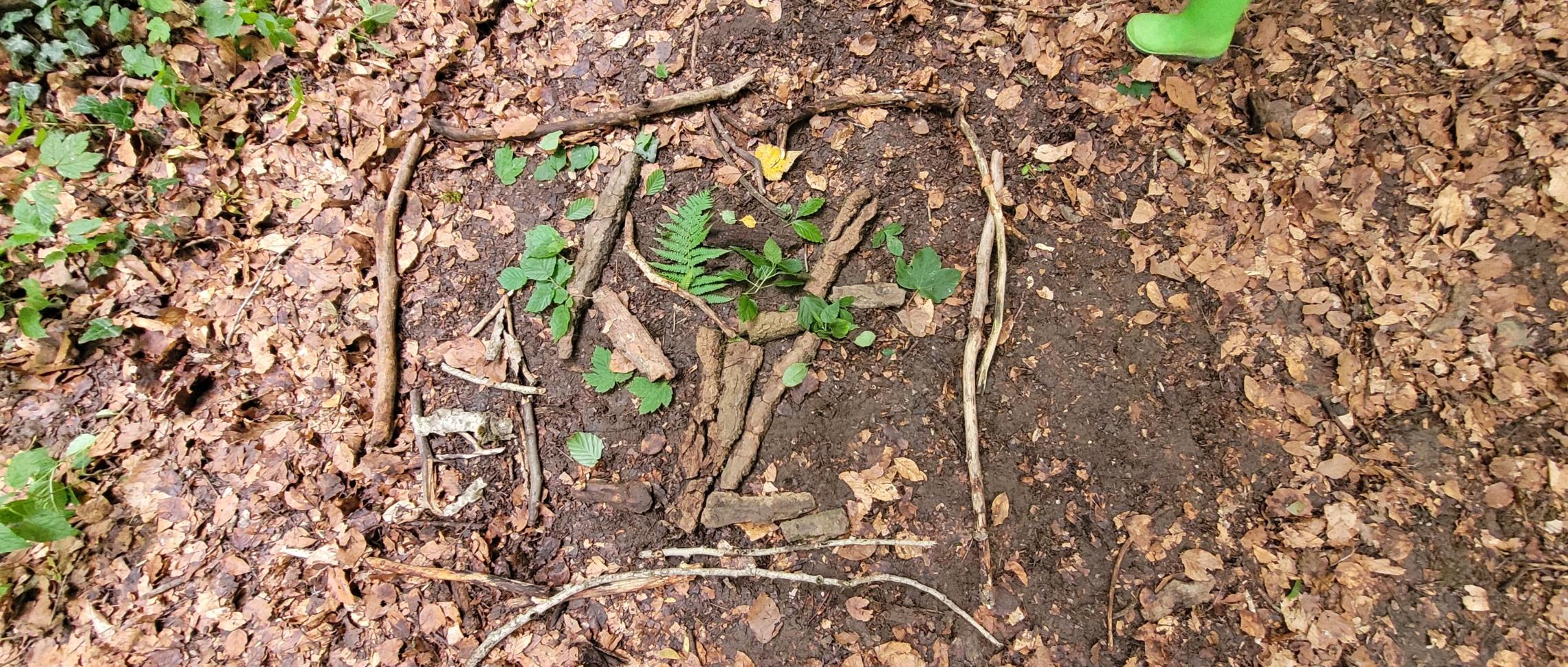 Aus Blättern und Stöcken legen wir wunderschöne Bilder auf dem Waldboden.
