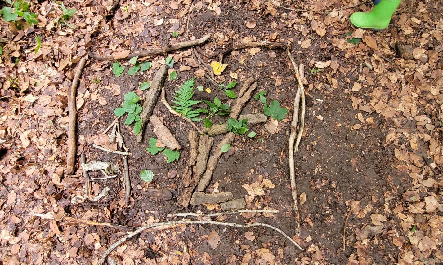 Aus Blättern und Stöcken legen wir wunderschöne Bilder auf dem Waldboden.